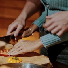 two people are cutting up food on a table