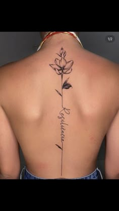 the back of a woman's neck with flowers and words tattooed on her lower back