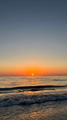 the sun is setting over the ocean with waves