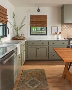 a kitchen with wooden floors and green cabinets, an area rug in front of the sink