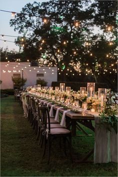 a long table set up with candles and greenery for an outdoor dinner party in the evening