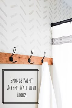 a white towel hanging on the wall next to a black and white sign that says sponge paint accent wall with hooks