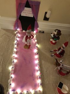 an elf's bed is decorated with fairy lights and stuffed animals on the floor