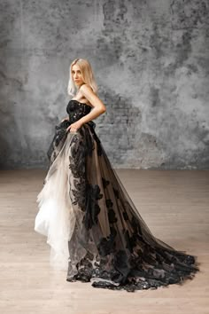 a woman in a black and white dress standing on a wooden floor next to a wall