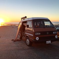 a van parked on the beach at sunset