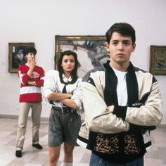 three people standing in an art gallery with their arms crossed