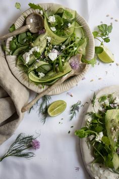 two plates filled with food sitting on top of a white tablecloth covered in green leaves