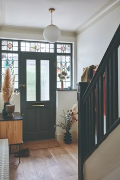 an entryway with stained glass windows and wooden stairs leading up to the front door