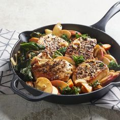 a skillet filled with meat and vegetables on top of a table