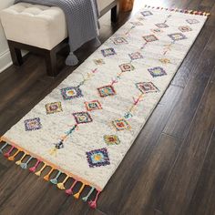 a white rug with colorful tassels on the floor