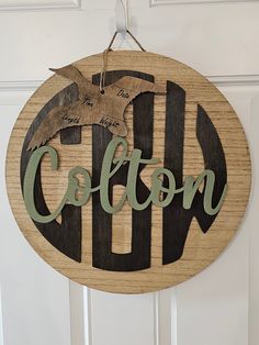 a wooden sign hanging on the front door of a house that says collon with an eagle flying over it