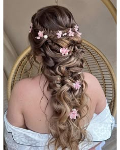 a woman with long hair and flowers in her hair is sitting on a wicker chair