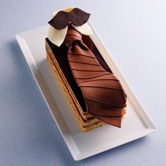 a piece of cake on a white plate with a chocolate bow tie on it's top