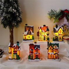 lighted houses on display in front of a christmas tree