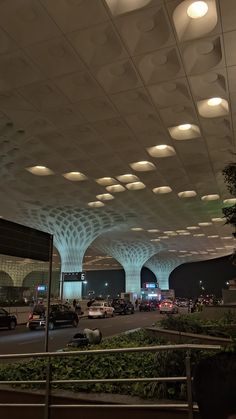 an airport terminal with many cars parked in the parking lot and lights on overhead ceiling