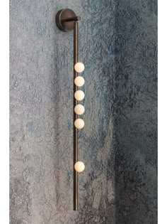 a bathroom light with five balls hanging from it's arm and on the wall