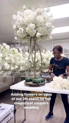 a woman standing in front of a table with flowers on it and the words adding flowers on base of our stand for our magnificent couple's wedding