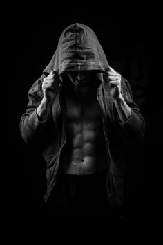 black and white photograph of a shirtless man with his hands on his head in the dark