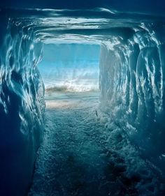 an ice cave in the ocean with light coming from it's entrance and water below