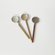 three wooden spoons and two metal measuring spoons on a white surface