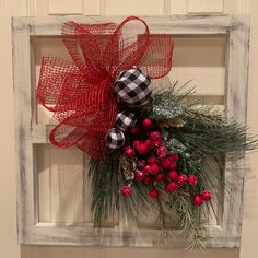 a christmas wreath hanging on the side of a white door with red and green decorations