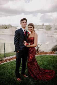 a man and woman standing next to each other in front of a body of water