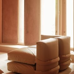 a couch sitting on top of a floor in front of two large windows with the sun shining through them