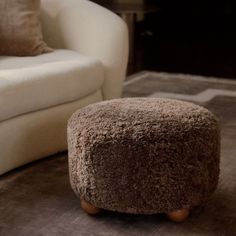 a brown ottoman sitting on top of a rug next to a white chair