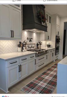 a kitchen with white cabinets and black stove top hood over the range in front of an oven