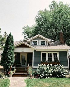 a gray house with white flowers and trees