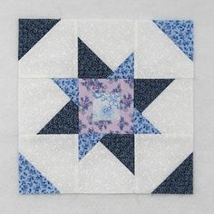 a blue and white patchwork quilt with a star design on the center, in front of a gray background