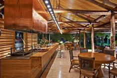 an outdoor restaurant with wooden tables and chairs under a roof that is lit up at night