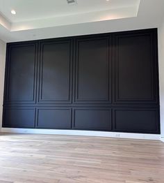 an empty room with black paneling and wood floors in the center is painted white