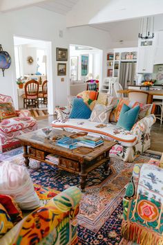 a living room filled with lots of furniture and colorful pillows on top of it's couches