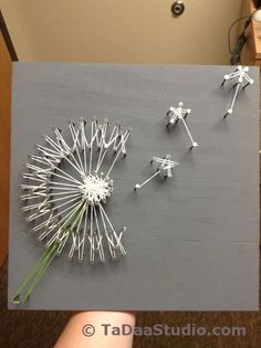 the dandelion is made out of pins and sticks, which are attached to a piece of wood