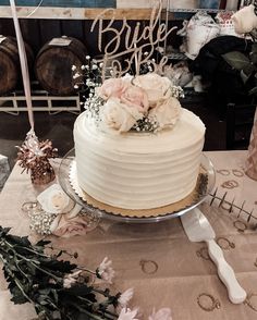 a white wedding cake sitting on top of a table next to flowers and greenery