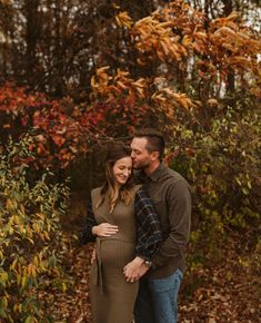 a pregnant couple standing in front of some trees