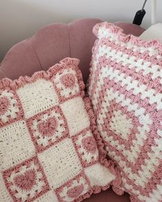 two crocheted pillows sitting on top of a pink chair