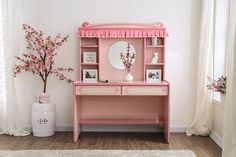 a pink desk with a mirror and vase on it