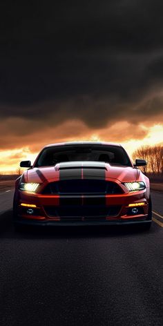 a red sports car is driving down the road at night with dark clouds in the background