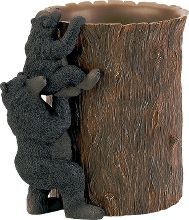 two teddy bears are climbing up the side of a tree stump as if they were hugging