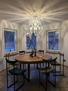 a dining room table with four chairs and a chandelier hanging from the ceiling