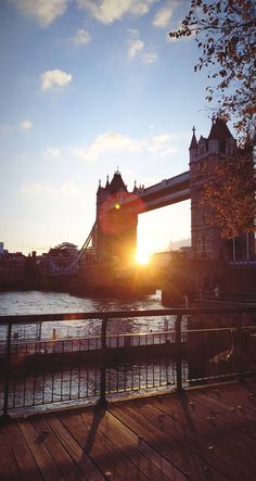 the sun is setting over tower bridge in london