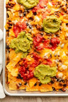 a casserole dish with tortilla chips and guacamole on top