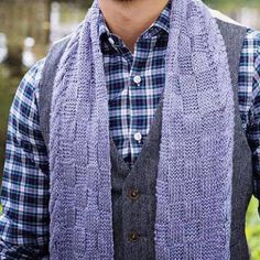 a man wearing a plaid shirt and vest with a knitted scarf around his neck