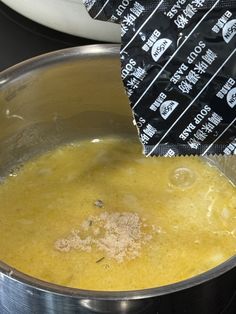 a silver pot filled with yellow liquid next to a white bowl