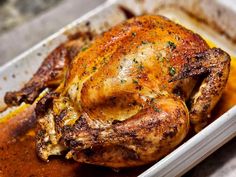 a roasted chicken in a baking dish with gravy