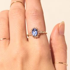 a woman's hand holding a ring with a blue stone