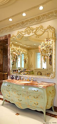 an ornately decorated bathroom with chandelier and large mirror above it, along with marble flooring