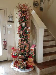 a christmas tree decorated with gingerbreads and candy canes is on the stairs